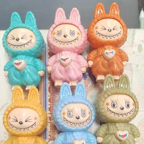Set of colorful cartoon character figurines with bunny ears on a white surface.