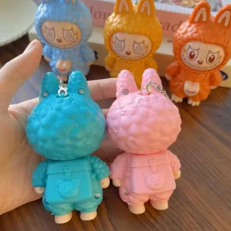 Colorful animal-themed keychains held by a hand on a wooden surface.
