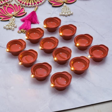 Decorative oil lamps (diyas) on a white surface with decorative elements.