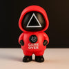 Toy figure in a red hood with 'GAME OVER' text on a dark background