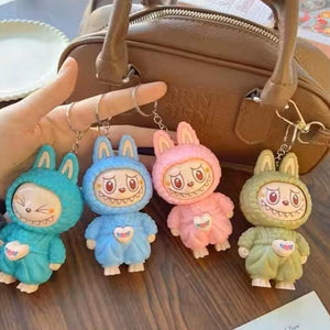 Four colorful keychains shaped like cartoon characters in bunny costumes on a wooden surface.