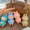 Four colorful keychains shaped like cartoon characters in bunny costumes on a wooden surface.